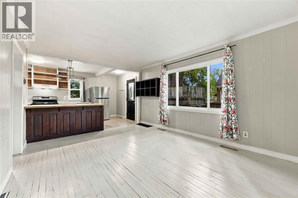 Open concept living area and kitchen with wooden island and view out window. - 178 East Street North, Sarnia