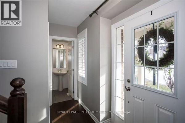 Interior entryway with dark hardwood floors, gray walls, and a door to a powder room. - 178 Flowing Creek Circle, Ottawa