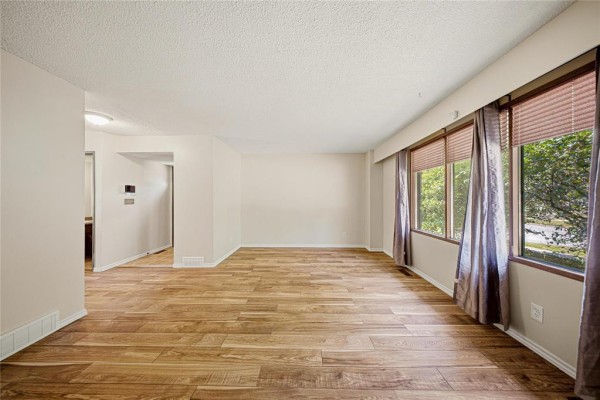 Living room with large windows, hardwood floors, and an open doorway leading to another room. - 178 Pentland Street, Winnipeg
