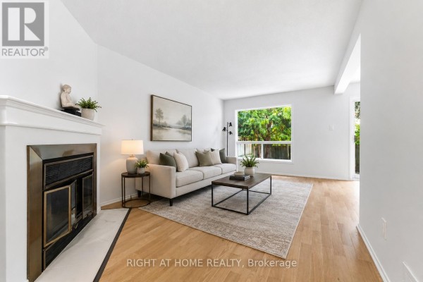 Living room with a fireplace, sofa, coffee table, and a large window. - 178 Presland Road, Ottawa