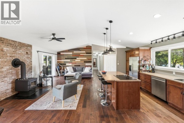 Open concept living area with kitchen, dining, and seating areas, featuring a brick fireplace. - 178 Range Road, Kaleden