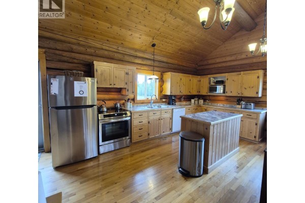 A spacious kitchen with light wood cabinets, stainless steel appliances, and a central island. - 17849 Langston Road, Vanderhoof