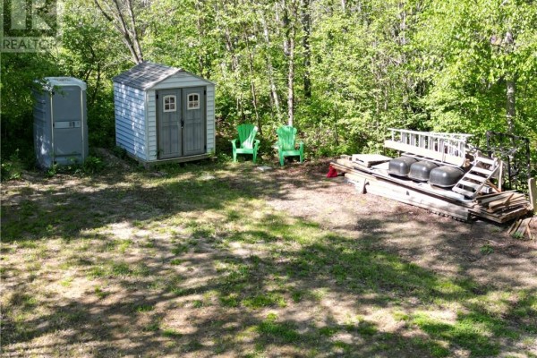 Outdoor shed, porta-potty, two green chairs, and a floating dock on a grassy area. - 1789 Highway 575, Field
