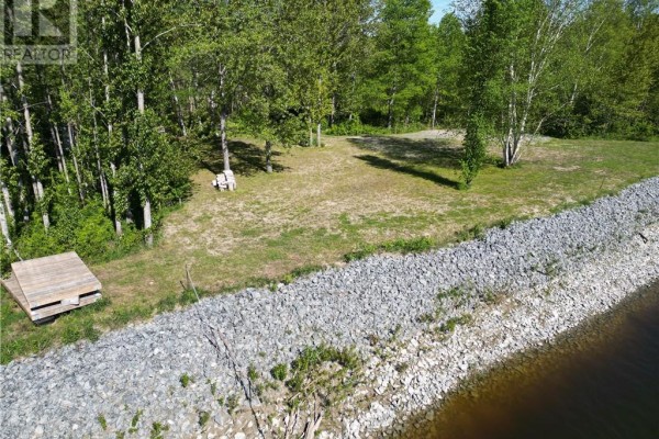 Waterfront view of a property with a retaining wall made of grey rocks and a small wooden dock. - 1789 Highway 575, Field