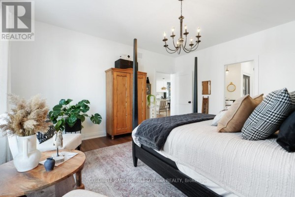 A bedroom with a four-poster bed, wooden wardrobe, and a seating area with plants. - 179 Glenncastle Drive, Ottawa