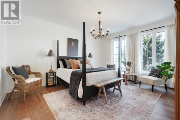 Spacious primary bedroom with a large bed, sitting area, chandelier, and large windows. - 179 Glenncastle Drive, Ottawa