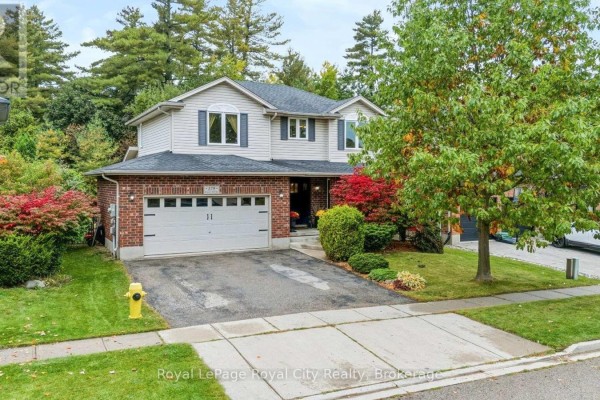 A wide-angle exterior shot showcasing the front facade of a residence with manicured landscaping and trees. - 179 Granite Hill Road, Cambridge