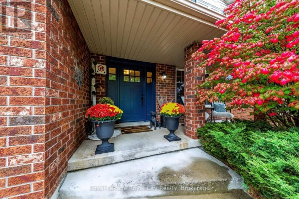 Close-up of a covered front porch with a blue front door, red brick pillars, and decorative urns. - 179 Granite Hill Road, Cambridge