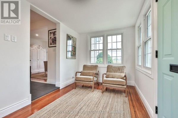Interior entryway with two beige armchairs, a jute rug, and wood floors. - 179 Niagara Street, Niagara On The Lake