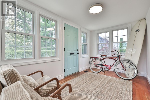 Sunroom with light blue door, two chairs, vintage bicycle, and surfboard. - 179 Niagara Street, Niagara On The Lake