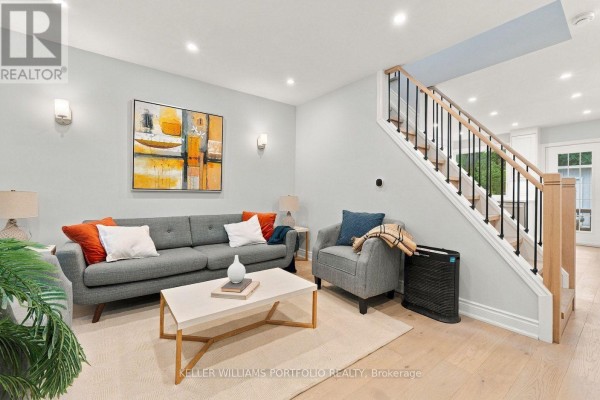 Living room with grey sofa, chairs, coffee table, and stairs. - 179 Oakcrest Avenue, Toronto