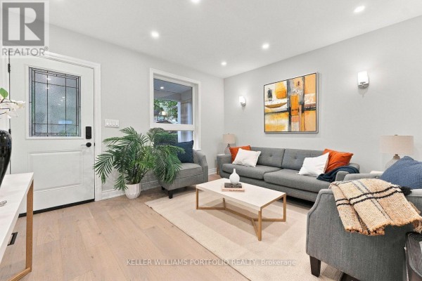 Living room with a sofa, two chairs, coffee table, and front door. - 179 Oakcrest Avenue, Toronto