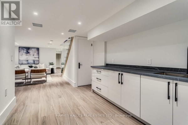 Modern kitchen with white cabinets & dark countertops next to living area - 179 Palmerston Avenue Toronto