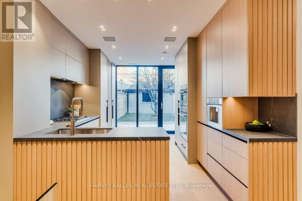 Modern kitchen with wood accents, ovens, and sliding glass door - 179 Palmerston Avenue Toronto