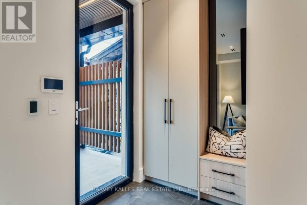Living room with light wood floors, abstract art, and glass doors leading outside. - 179 Palmerston Avenue, Toronto