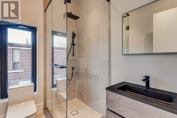 Modern bathroom with walk-in shower, rainfall shower head, black sink, and vanity - 179 Palmerston Avenue Toronto