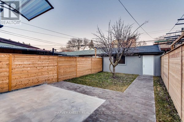 Backyard with paved patio, concrete pad, new wooden fence, and detached structure - 179 Palmerston Avenue Toronto