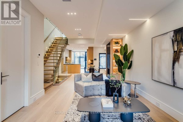 Modern living room with glass staircase and built-in shelving - 179 Palmerston Avenue Toronto
