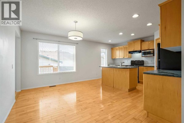 Primary bedroom with a king-size bed, dresser, armchair, and a ceiling fan. - 179 Prestwick Drive Se, Calgary