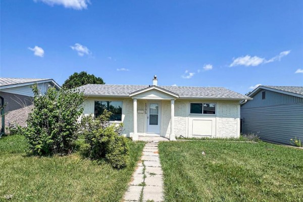 View of the front exterior of a single-story cream house with white trim and a manicured lawn. - 1795 Manitoba Avenue, Winnipeg