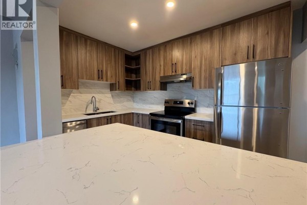 Island view of kitchen with light wood cabinets, stainless steel appliances, and marble tile backsplash. - 1797 Main Street W Unit# 18, Hamilton