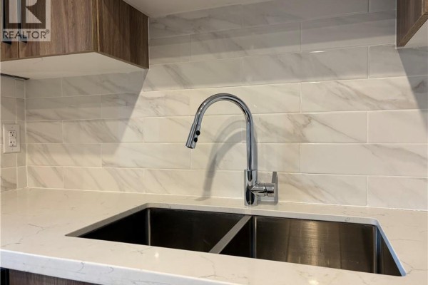 Double stainless steel sink with chrome faucet and marble tile backsplash in the kitchen. - 1797 Main Street W Unit# 18, Hamilton