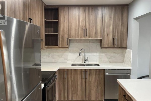 Kitchen with light wood cabinets, white countertops, stainless steel appliances, and a double sink. - 1797 Main Street W Unit# 3, Hamilton