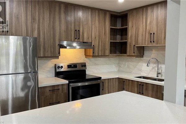 Corner kitchen with stainless steel appliances, wood-look cabinetry, and white quartz countertops. - 1797 Main Street W Unit# 3, Hamilton