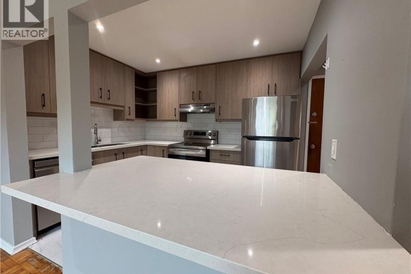 Open concept kitchen with a large island featuring white quartz countertops and light wood cabinets. - 1797 Main Street W Unit# 4, Hamilton