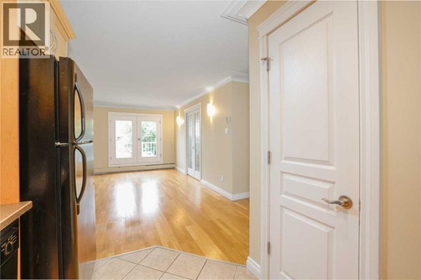 Kitchen with light wood cabinets, black appliances, and beige tile flooring. - 18, 1813 25 Avenue Sw, Calgary