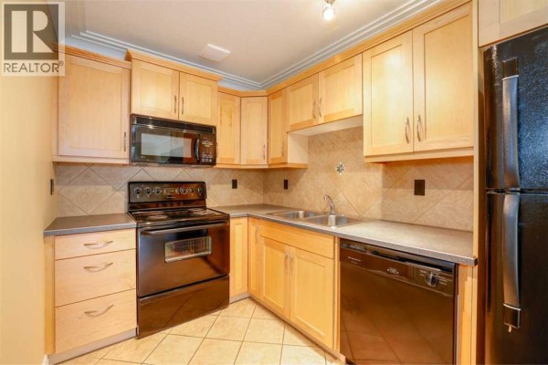 Combined kitchen and living area with light wood cabinets and hardwood floors. - 18, 1813 25 Avenue Sw, Calgary
