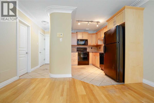 View from the kitchen into the living room with double doors leading outside. - 18, 1813 25 Avenue Sw, Calgary