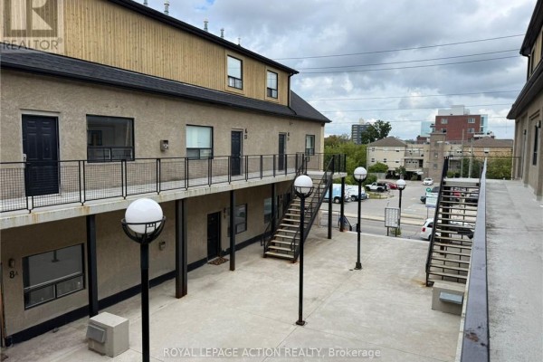 View of apartment building exterior with outdoor corridors, staircases, and parking lot visible. - 18 - 12 Bridgeport Road E, Waterloo