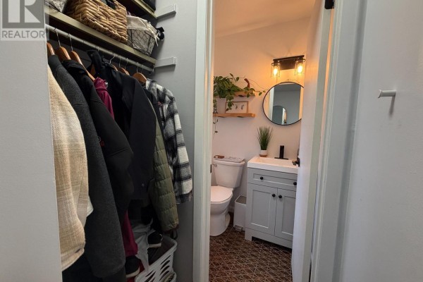 View of a powder room with a toilet, vanity, and mirror from a coat closet. - 18 - 2 Paradise Boulevard, Ramara