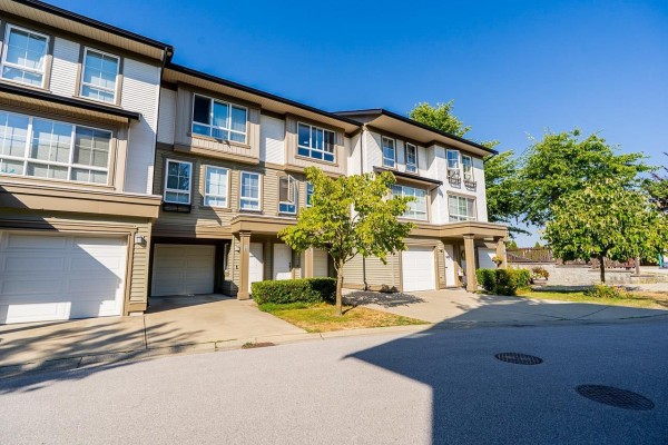 Front exterior of a townhouse complex with attached garages and large windows. - 18 19505 68a Avenue, Surrey