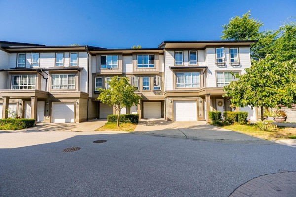 Street view of a townhouse complex with multiple units, garages, and trees. - 18 19505 68a Avenue, Surrey