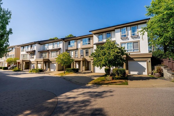 Side angle view of a townhouse complex showing several units and garages. - 18 19505 68a Avenue, Surrey