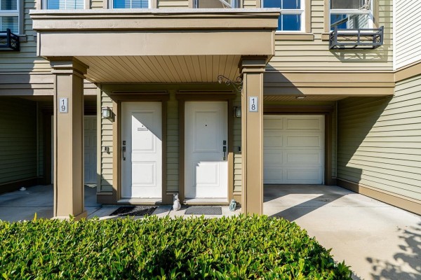 Close-up of two townhouse entrances numbered 18 and 19, with a garage door. - 18 19505 68a Avenue, Surrey