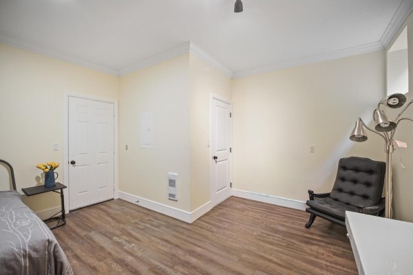Bedroom with light yellow walls, wood-look flooring, a bed, and a black armchair. - 18 45390 Vedder Mountain Road, Vedder Mountain, Cultus Lake