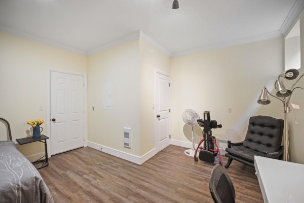 Room with light yellow walls, wood-look flooring, a bed, a black armchair, and medical equipment. - 18 45390 Vedder Mountain Road, Vedder Mountain, Cultus Lake