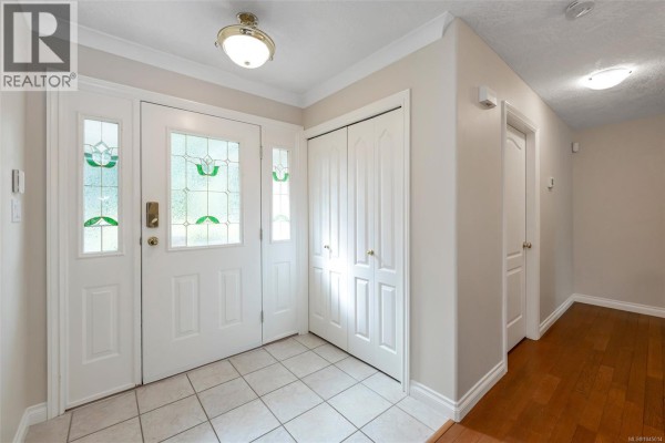Interior entryway with tiled floor, white double closet doors, and hardwood hallway. - 18 6000 St. Ann's Dr, Duncan