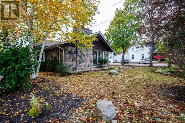 Side view of the stone bungalow with trees and a residential street in the background. - 18 Adamson Street S, Halton Hills