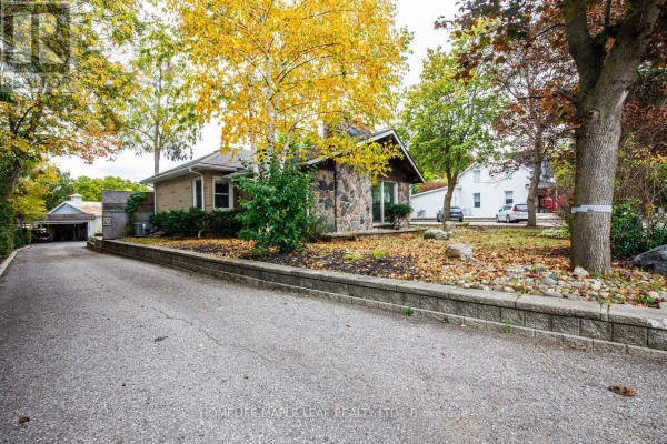 Driveway leading up to the stone bungalow with a detached garage on the left. - 18 Adamson Street S, Halton Hills