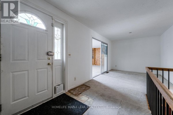 Interior entryway with a white door, carpeted floor, and view into a living area. - 18 Adamson Street S, Halton Hills