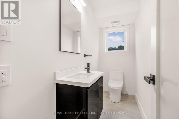 Powder room with a modern vanity, white countertop, and a white toilet under a small window. - 18 Alderwood Lane, Barrie