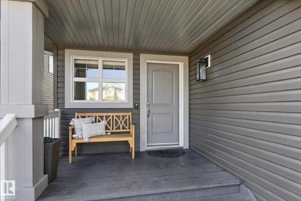 Covered front porch with a grey door, window, and wooden bench. - 18 Altadena, Sherwood Park
