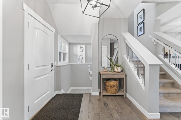 Entrance hallway with a white door, white staircase, and a mirrored console table. - 18 Altadena, Sherwood Park