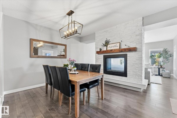 Dining room with a wooden table, black chairs, and a white stone fireplace. - 18 Altadena, Sherwood Park