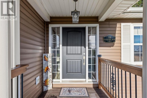 Front entrance with a dark gray door, sidelights, and address plaque. - 18 Cedar Avenue, Charlottetown