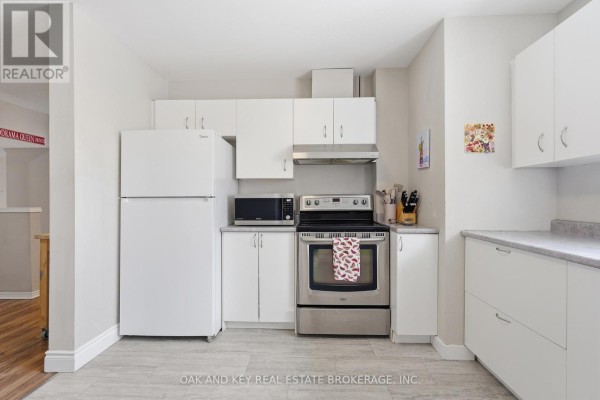 Kitchen with white appliances, cabinets, and wood-look flooring - 18 Chapman Court London North